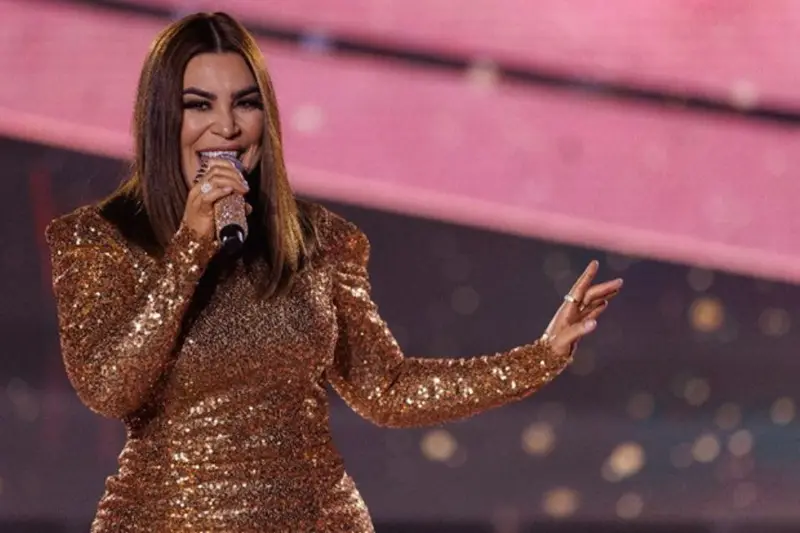Cantora de vestido dourado cantando ao microfone em um palco
