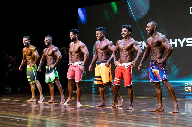 Atletas de fisiculturismo enfileirados no palco de um campeonato