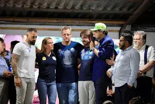 Grupo de pessoas reunidas em pé em um encontro sob cobertura