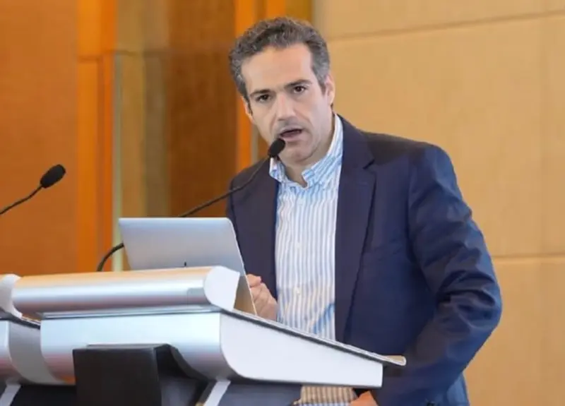 Homem de terno discursando em um púlpito com microfone