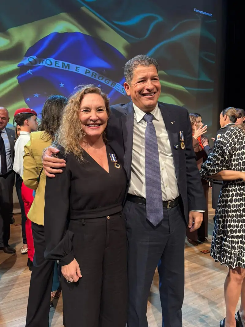Claudine Fernandes de Araújo posando ao lado de um homem com medalha em uma solenidade