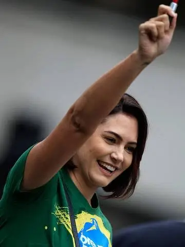 Michelle Bolsonaro sorrindo com o braço erguido