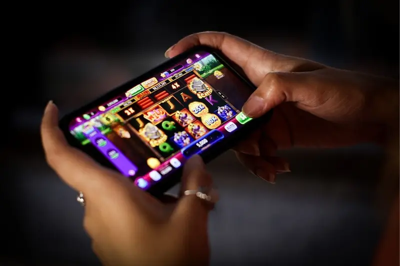 Mãos segurando um celular com jogo de cassino online na tela