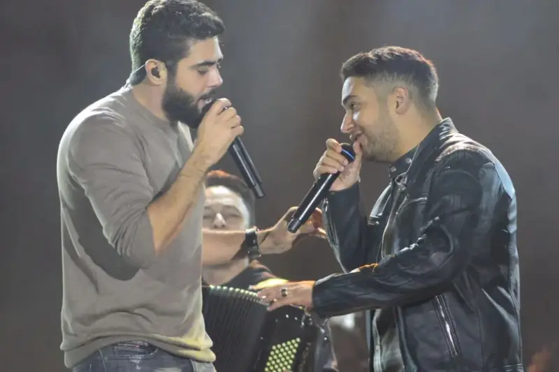 Dupla sertaneja cantando ao microfone em um show
