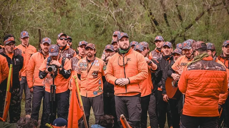 Grupo de voluntários com uniformes laranja reunidos ao ar livre