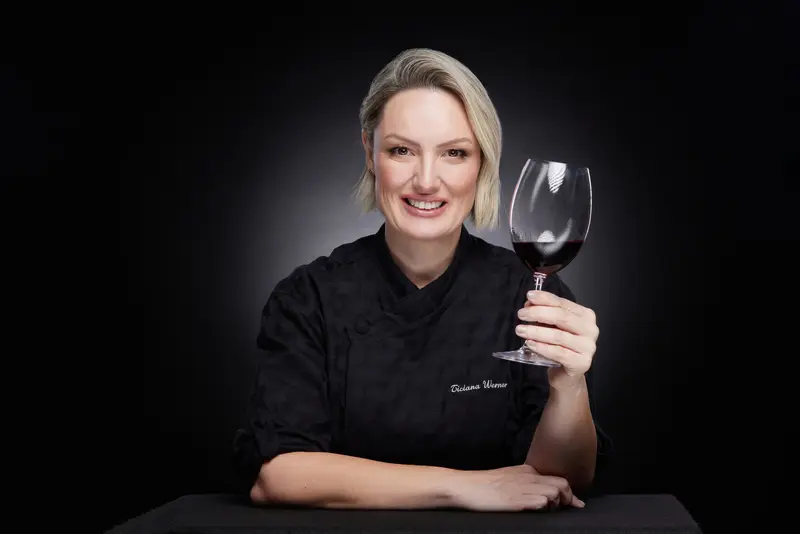 Ticiana Werner sorrindo e segurando uma taça de vinho tinto