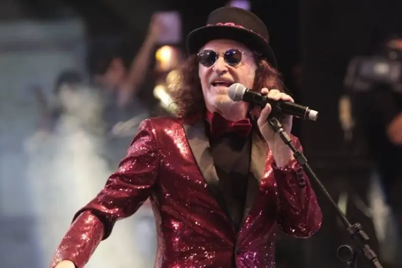 Cantor de terno vermelho brilhante e chapéu cantando ao microfone