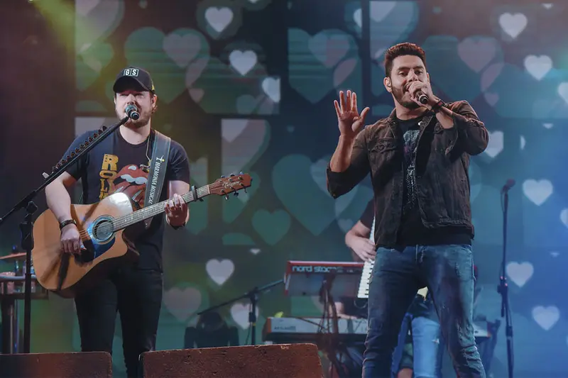 Dupla sertaneja cantando e tocando violão no palco