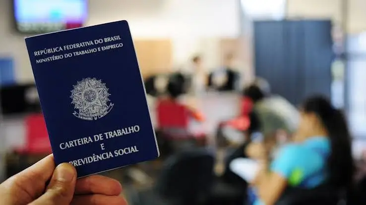 Mão segurando uma Carteira de Trabalho e Previdência Social