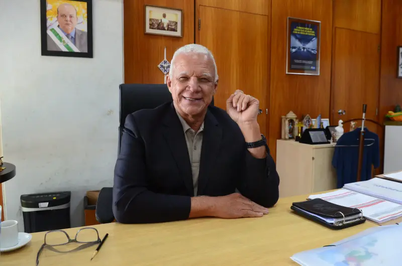 José Humberto sorrindo sentado em sua mesa de trabalho