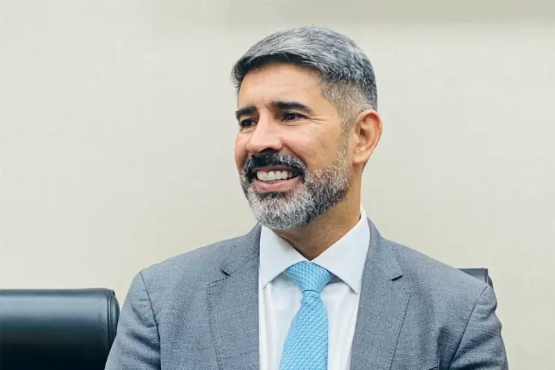 Homem grisalho de terno sorrindo em um escritório