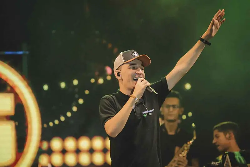 Cantor de boné com o braço erguido em um show