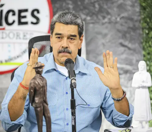 Nicolás Maduro falando ao microfone com as mãos erguidas