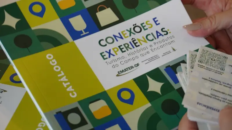 Mão segurando o catálogo Conexões e Experiências de turismo rural da Emater-DF
