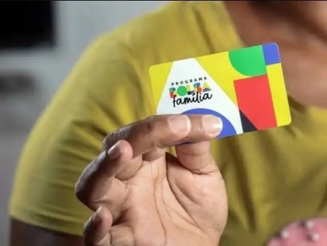 Mão segurando o cartão do programa Bolsa Família