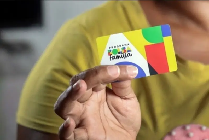 Mão segurando o cartão do programa Bolsa Família