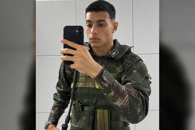 Jovem de farda camuflada do Exército tirando foto no espelho com o celular